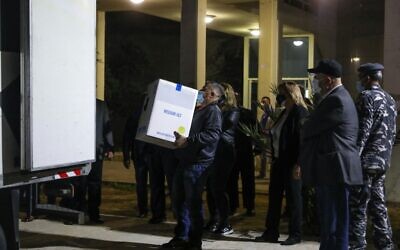 Members of Lebanese security forces and staff look on during the unloading of boxes of the first shipment of the COVID-19 Pfizer-BioNTech vaccine, upon arrival to Rafic Hariri University Hospital in the capital Beirut, on February 13, 2021. (ANWAR AMRO / AFP)
