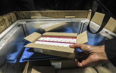 A Palestinian health workers stores the first arriving shipment of doses of Russia's Sputnik V vaccine for COVID-19 coronavirus disease in a preservation refrigerator in Gaza City on February 17, 2021. (MAHMUD HAMS / AFP)