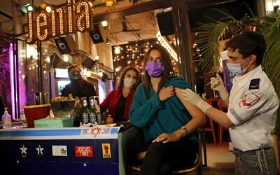 A health worker administers the COVID-19 vaccine to an Israeli at a bar in Tel Aviv, on February 18, 2021. (Gil Cohen-Magen/AFP)