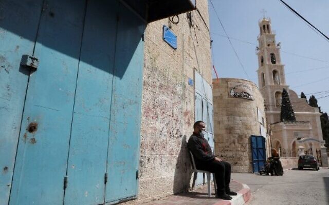A Palestinian man wearing a protective mask sits outside a closed shop in the West Bank town of Beit Sahur, near Bethlehem amid a tightened lockdown due to the COVID-19 pandemic on February 24, 2021. (Photo by HAZEM BADER / AFP) A Palestinian man wearing a protective mask sits outside a closed shop in the West Bank town of Beit Sahur, near Bethlehem amid a tightened lockdown due to the COVID-19 pandemic on February 24, 2021. (Photo by HAZEM BADER / AFP)