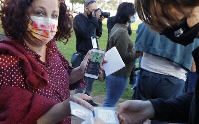 A woman shows her 'Green Pass' before entering a concert for vaccinated seniors, organized by the municipality of Tel Aviv, on February 24, 2021. (JACK GUEZ / AFP)