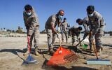 Volunteers from youth associations clean a contaminated beach in the southern Lebanese city of Tyre on February 27, 2021, following last week's offshore oil spill that drenched the northern Israeli coastline and reached parts of the neighboring Lebanese beaches. (Mahmoud ZAYYAT / AFP)