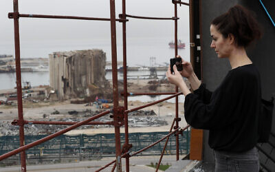 Joana Dagher, 33, who lost her memory for two full months from the trauma she suffered in the massive August explosion at the Beirut port, including a cerebral contusion and brain lesions, takes pictures of the explosion scene from her damaged apartment rooftop, in Beirut, Lebanon, January 27, 2021. (Hussein Malla/AP)