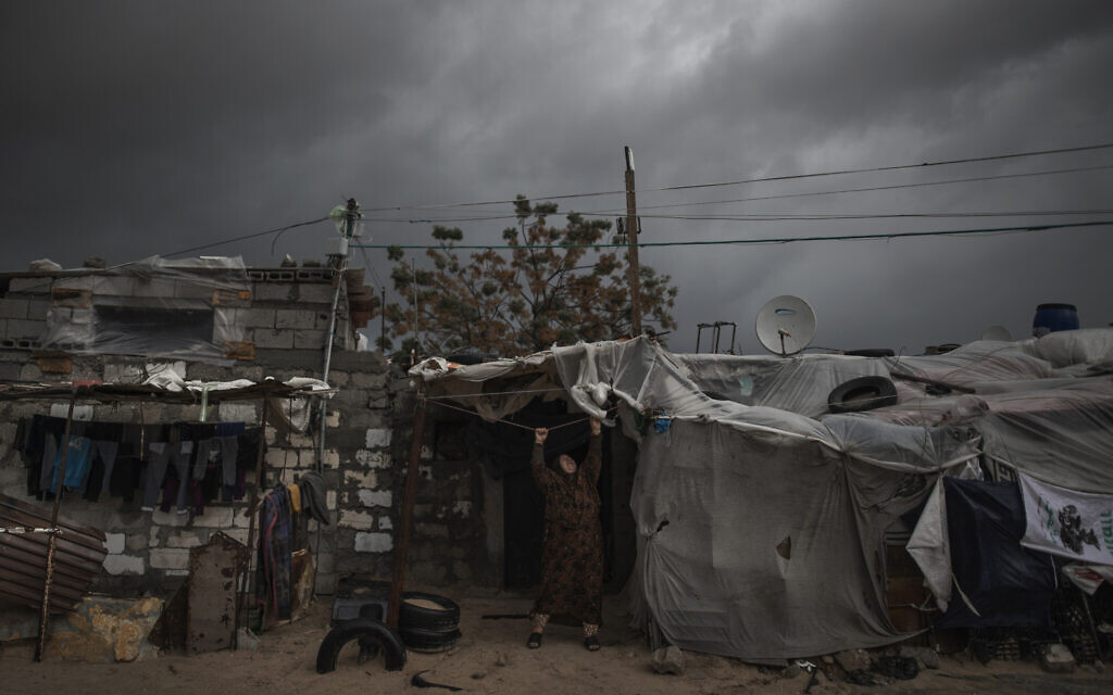 A Palestinian woman checks the nylon cover on the roof of her house on a rainy day in a poor neighborhood of Khan Younis, in the southern Gaza StripJan. 20, 2021. (AP Photo/Khalil Hamra, File) A Palestinian woman checks the nylon cover on the roof of her house on a rainy day in a poor neighborhood of Khan Younis, in the southern Gaza StripJan. 20, 2021. (AP Photo/Khalil Hamra, File)