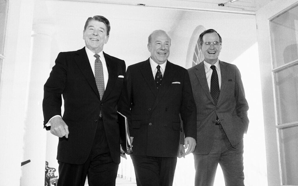 Then-secretary of state George Shultz, center, walks with then-president Ronald Reagan and vice president George Bush upon his arrival at the White House in Washington, after two days of arms talks with the Soviet Union in Geneva, on January 9, 1985. (AP Photo/Barry Thumma, File)