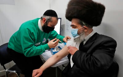 Rabbi Bieberfeld is administered a dose of the AstraZeneca coronavirus vaccine at an event to encourage vaccine uptake in Britain's Haredi Orthodox Jewish community at the John Scott Vaccination Centre in London, February 13, 2021. (AP Photo/Frank Augstein)