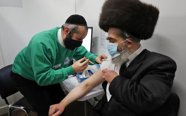 Rabbi Bieberfeld is administered a dose of the AstraZeneca coronavirus vaccine at an event to encourage vaccine uptake in Britain's Haredi Orthodox Jewish community at the John Scott Vaccination Centre in London, February 13, 2021. (AP Photo/Frank Augstein)