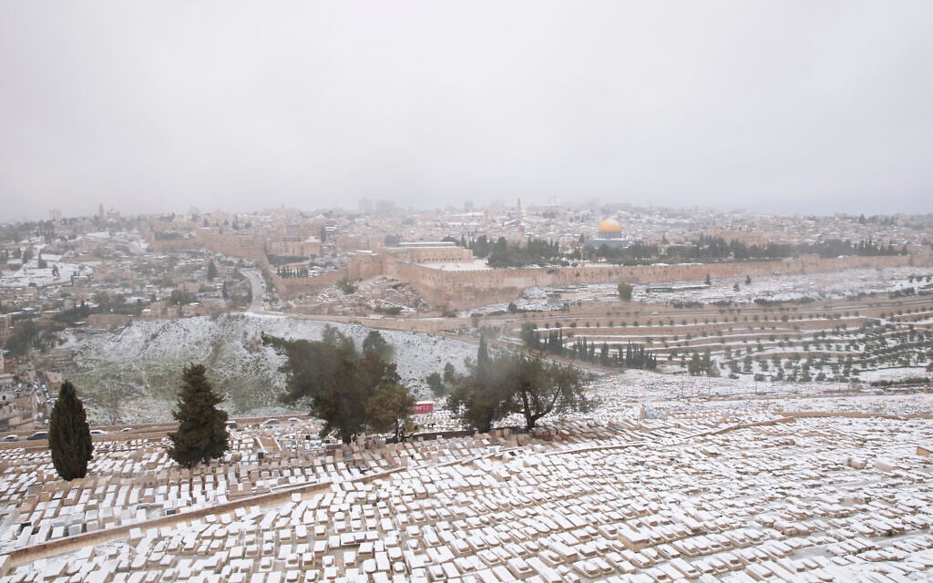 Snow covers the Mount of Olives Jewish cemetery with a view of the Dome of the Rock in the background, in Jerusalem, Thursday, Feb. 18, 2021. (AP Photo/Oded Balilty)