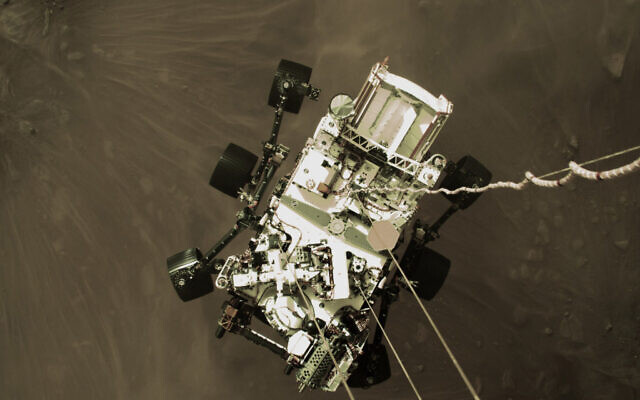 This Thursday, Feb. 18, 2021 photo provided by NASA shows the Perseverance rover lowered towards the surface of Mars during its powered descent. (NASA via AP) This Thursday, Feb. 18, 2021 photo provided by NASA shows the Perseverance rover lowered towards the surface of Mars during its powered descent. (NASA via AP)