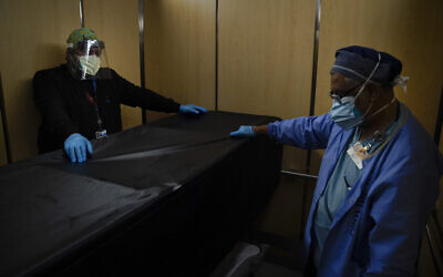 In this Jan. 9, 2021, file photo, transporters Miguel Lopez, right, Noe Meza move a body of a COVID-19 patient to a morgue at Providence Holy Cross Medical Center in the Mission Hills section of Los Angeles.(AP Photo/Jae C. Hong, File)