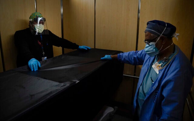 In this Jan. 9, 2021, file photo, transporters Miguel Lopez, right, Noe Meza move a body of a COVID-19 patient to a morgue at Providence Holy Cross Medical Center in the Mission Hills section of Los Angeles.(AP Photo/Jae C. Hong, File) In this Jan. 9, 2021, file photo, transporters Miguel Lopez, right, Noe Meza move a body of a COVID-19 patient to a morgue at Providence Holy Cross Medical Center in the Mission Hills section of Los Angeles.(AP Photo/Jae C. Hong, File)