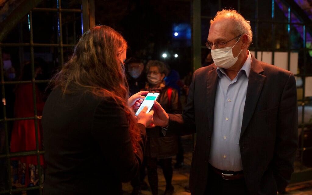 A man presents his Green Pass, proof that he is vaccinated against the coronavirus, on opening night at the Khan Theater for a performance where all guests were required to show proof of vaccination or full recovery from the virus, in Jerusalem, February 23, 2021. (AP/Maya Alleruzzo) A man presents his Green Pass, proof that he is vaccinated against the coronavirus, on opening night at the Khan Theater for a performance where all guests were required to show proof of vaccination or full recovery from the virus, in Jerusalem, February 23, 2021. (AP/Maya Alleruzzo)