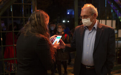 A man presents his Green Pass, proof that he is vaccinated against the coronavirus, on opening night at the Khan Theater for a performance where all guests were required to show proof of vaccination or full recovery from the virus, in Jerusalem, February 23, 2021. (AP/Maya Alleruzzo)