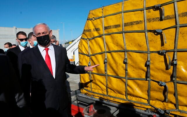 Prime Minister Benjamin Netanyahu attends the arrival of over 100,000 doses of the Pfizer coronavirus vaccine, at Ben Gurion Airport, on December 9, 2020. (Abir Sultan/Pool Photo via AP) Prime Minister Benjamin Netanyahu attends the arrival of over 100,000 doses of the Pfizer coronavirus vaccine, at Ben Gurion Airport, on December 9, 2020. (Abir Sultan/Pool Photo via AP)