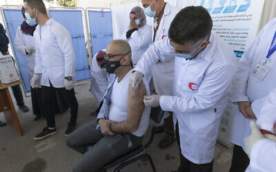 A medic administers a Moderna COVID-19 vaccine to a fellow medic during a campaign to vaccinate front-line medical workers, at the health ministry, in the West Bank city of Bethlehem on Feb. 3, 2021. (AP/Nasser Nasser)
