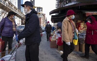 Shoppers walk with their purchases, Monday, Feb. 8, 2021, in the Chinatown neighborhood of New York. (AP Photo/Mark Lennihan)