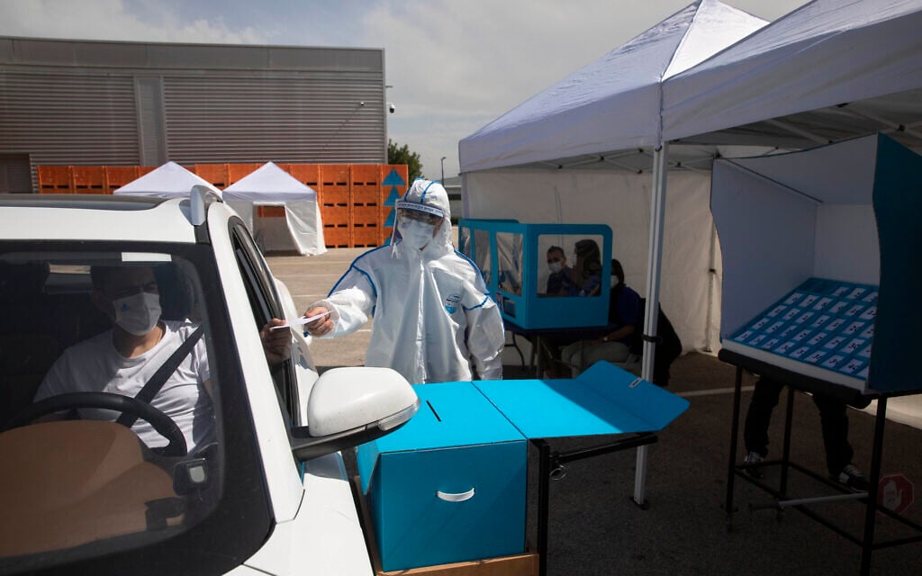 Workers show a drive-by voting station during a media tour demonstration of coronavirus measures prior to upcoming elections, at the central elections logistics center in Shoham, Israel, Tuesday, February 23, 2021. (AP/Sebastian Scheiner) Workers show a drive-by voting station during a media tour demonstration of coronavirus measures prior to upcoming elections, at the central elections logistics center in Shoham, Israel, Tuesday, February 23, 2021. (AP/Sebastian Scheiner)