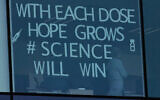 An employee works behind a window with a message taped to it at Pfizer Manufacturing in Puurs, Belgium on February 25, 2021. (Virginia Mayo/AP)