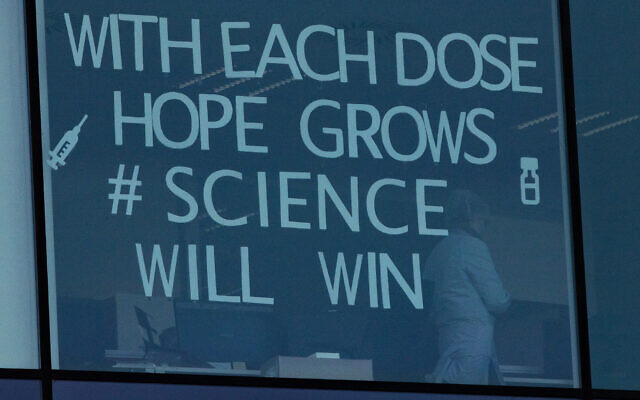 An employee works behind a window with a message taped to it at Pfizer Manufacturing in Puurs, Belgium on February 25, 2021. (Virginia Mayo/AP) An employee works behind a window with a message taped to it at Pfizer Manufacturing in Puurs, Belgium on February 25, 2021. (Virginia Mayo/AP)