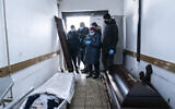 Relatives stand next to a coffin with the body of a patient who died from the coronavirus at a morgue of the regional hospital in Ivano-Frankivsk, 430 kilometers southwest of the capital, Kyiv, Ukraine on Feb. 26, 2021. (AP/Evgeniy Maloletka)