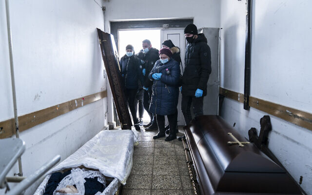 Relatives stand next to a coffin with the body of a patient who died from the coronavirus at a morgue of the regional hospital in Ivano-Frankivsk, 430 kilometers southwest of the capital, Kyiv, Ukraine on Feb. 26, 2021. (AP/Evgeniy Maloletka) Relatives stand next to a coffin with the body of a patient who died from the coronavirus at a morgue of the regional hospital in Ivano-Frankivsk, 430 kilometers southwest of the capital, Kyiv, Ukraine on Feb. 26, 2021. (AP/Evgeniy Maloletka)