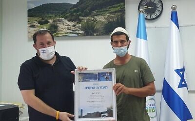Eitan Ze'ev, right, receives an award from the head of the Samaria Regional Council, Yossi Dagan, on September 2, 2020, for his involvement in a clash with Palestinians over a piece of agricultural land that summer. (Roi Hadi)