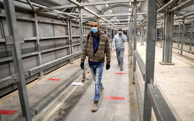 Palestinian workers enter Israel through the Mitar checkpoint in the West Bank city of Hebron, on May 5, 2020. (Wisam Hashlamoun/ Flash90)