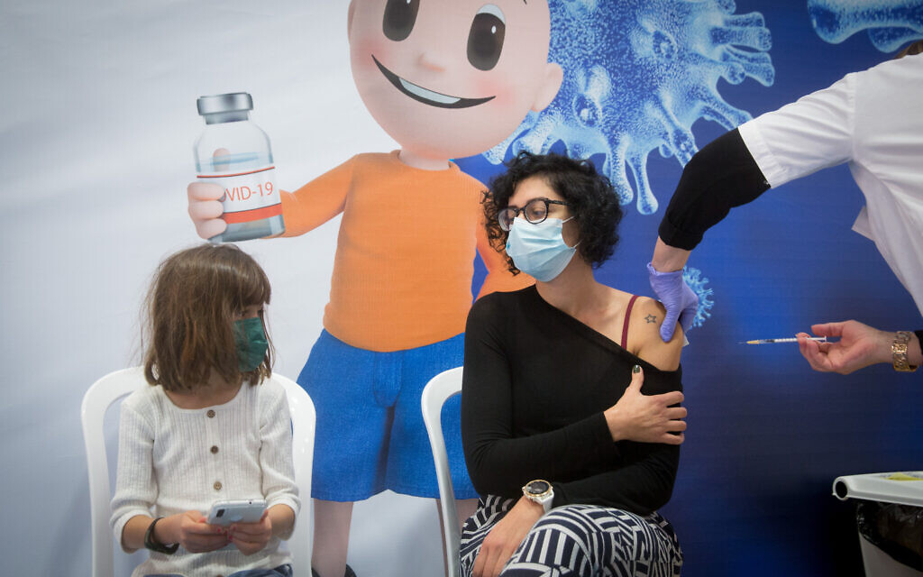 People receive a COVID-19 vaccine, at a sports hall turned into a vaccination center in Hod haSharon, February 2, 2021. (Miriam Alster/Flash90)