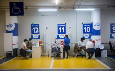 Israelis recieve a COVID-19 vaccine at a Maccabi Health vaccination center at the Givatayim mall, outside of Tel Aviv, February 4, 2021. (Miriam Alster/Flash90)