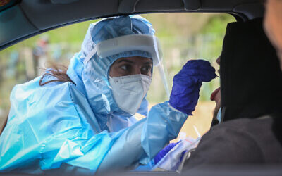 A medical worker at a drive-through site to collect samples for coronavirus testing in the northern Israeli city of Safed on February 8, 2021. (David Cohen/Flash90) A medical worker at a drive-through site to collect samples for coronavirus testing in the northern Israeli city of Safed on February 8, 2021. (David Cohen/Flash90)