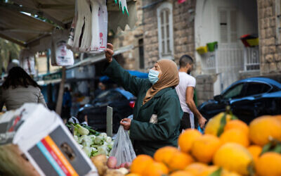 Illustrative: A woman shops in Wadi Nisnas in Haifa on February 5, 2021. (Shir Torem/Flash90)
