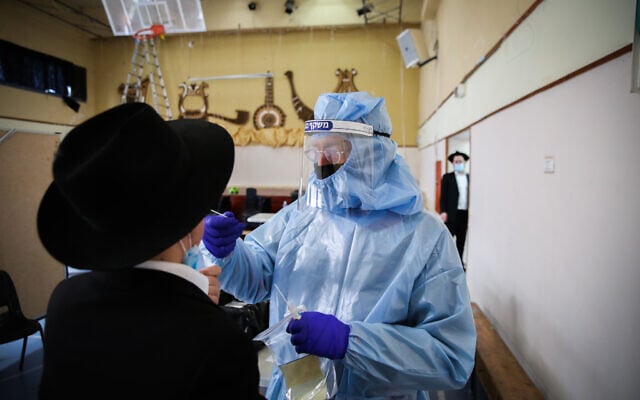 A medical worker tests an ultra-Orthodox man for coronavirus in Safed on February 10, 2021. (David Cohen/Flash90) A medical worker tests an ultra-Orthodox man for coronavirus in Safed on February 10, 2021. (David Cohen/Flash90)