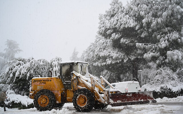 A tractor clears the snow off the ground in Kibbutz Marom Golan, in the Golan Heights February 17, 2021 (Michael Giladi/Flash90) A tractor clears the snow off the ground in Kibbutz Marom Golan, in the Golan Heights February 17, 2021 (Michael Giladi/Flash90)