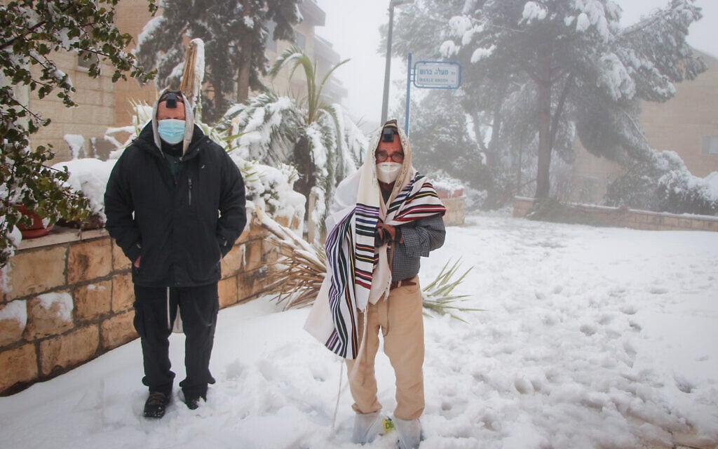 Men pray outside in the snow, in the West Bank settlement of Efrat, February 18, 2021 (Gershon Elinon/ Flash 90)