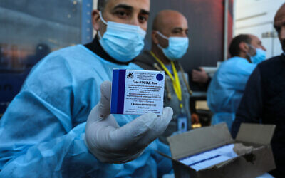 Palestinians from the Ministry of Health receive a shipment of the Russian Sputnik V coronavirus vaccine doses sent by the United Arab Emirates, after the Egyptian authorities allowed entry to Gaza through the Rafah crossing in the southern Gaza Strip, on February 21, 2021. (Abed Rahim Khatib/Flash90)