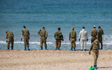 Israeli soldiers clean tar off the Palmachim beach following an offshore oil spill which hit most of the Israeli coastline. February 22, 2021. (Yonatan Sindel/Flash90)