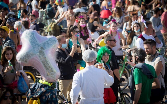 People wearing costumes celebrate the jewish holiday of Purim at Habima Square in Tel Aviv on February 26, 2021. (Miriam Alster/Flash90) People wearing costumes celebrate the jewish holiday of Purim at Habima Square in Tel Aviv on February 26, 2021. (Miriam Alster/Flash90)