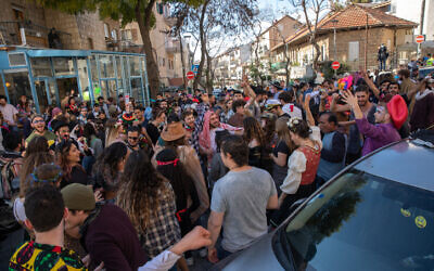 Young people dressed up in costumes during the Jewish holiday of Purim, dance at a street party in the neighborhood of Nahlaot in Jerusalem on February 28, 2021 (Olivier Fitoussi/Flash90)