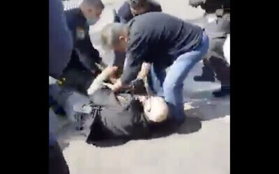 Police officers wrestle a shop owner in Holon to the ground to prevent him from stabbing himself, after he was fined for putting his merchandise on the sidewalk, February 24, 2021. (Screen capture: Twitter) Police officers wrestle a shop owner in Holon to the ground to prevent him from stabbing himself, after he was fined for putting his merchandise on the sidewalk, February 24, 2021. (Screen capture: Twitter)