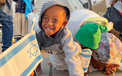 A girl smiles upon arriving from Ethiopia as her mother kisses the ground at Ben Gurion Airport in Israel on February 12, 2021. (Courtesy of ICEJ via JTA)