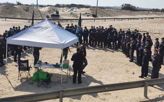 Police officers receive instructions at Nitzanim beach in southern Israel before joining volunteers to help clean up tar from an oil spill, February 22, 2021 (Menachem Fried/Israel Nature and Parks Authority) Police officers receive instructions at Nitzanim beach in southern Israel before joining volunteers to help clean up tar from an oil spill, February 22, 2021 (Menachem Fried/Israel Nature and Parks Authority)