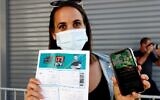 An attendee shows off a "green pass" (proof of being fully vaccinated against COVID-19 coronavirus disease) upon arrival at Bloomfield Stadium in Tel Aviv, on March 5, 2021, before attending a "green pass concert" for the vaccinated, organized by the Tel Aviv municipality. (Jack Guez/AFP)