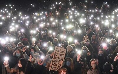 Well-wishers turn on their phone torches as they gather at a band-stand where a planned vigil in honor of murder victim Sarah Everard was cancelled after police outlawed it due to Covid-19 restrictions, on Clapham Common, south London on March 13, 2021  (JUSTIN TALLIS / AFP)