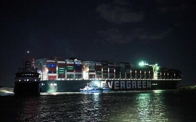 This picture taken late on March 27, 2021 shows a view of tugboats by the Panama-flagged MV 'Ever Given' container ship, which has been wedged diagonally across the span of the canal about six kilometers north of the Suez Canal's entrance by the Red Sea port city of Suez since March 23, blocking the waterway in both directions. (Ahmed HASAN / AFP)