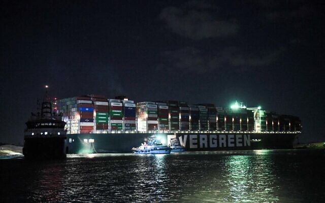 This picture taken late on March 27, 2021 shows a view of tugboats by the Panama-flagged MV 'Ever Given' container ship, which has been wedged diagonally across the span of the canal about six kilometers north of the Suez Canal's entrance by the Red Sea port city of Suez since March 23, blocking the waterway in both directions. (Ahmed HASAN / AFP) This picture taken late on March 27, 2021 shows a view of tugboats by the Panama-flagged MV 'Ever Given' container ship, which has been wedged diagonally across the span of the canal about six kilometers north of the Suez Canal's entrance by the Red Sea port city of Suez since March 23, blocking the waterway in both directions. (Ahmed HASAN / AFP)