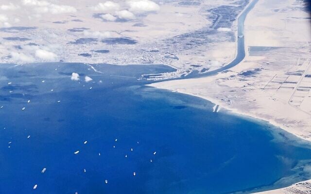 An aerial view taken on March 27, 2021 from the porthole of a commercial plane shows stranded ships waiting in queue in the Gulf of Suez to cross the Suez Canal at its southern entrance near the Red Sea port city of Suez, as the waterway remains blocked by the Panama-flagged container ship 'MV Ever Given,' which has remained wedged sideways about six kilometers north of the canal's entrance impeding all flowing traffic since March 23 (Mahmoud KHALED / AFP)
