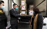 Chinese Ambassador Guo Wei (L) speaks with Palestinian Health Minister Mai al-Kaila during the unloading of a shipment of the Sinopharm COVID-19 vaccines donated by the Chinese government in the city of Ramallah in the West Bank, on March 29, 2021. (ABBAS MOMANI/AFP)