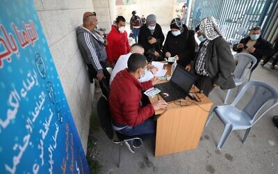 Palestinian Authority employees sign in West Bank Palestinians to be vaccinated against the coronavirus on March 21, 2021 (WAFA)