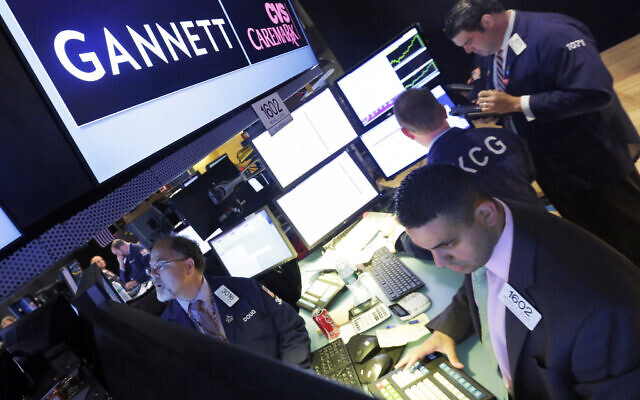 In this Aug. 5, 2014, file photo, specialist Michael Cacace, foreground right, works at the post that handles Gannett on the floor of the New York Stock Exchange. J(AP Photo/Richard Drew) In this Aug. 5, 2014, file photo, specialist Michael Cacace, foreground right, works at the post that handles Gannett on the floor of the New York Stock Exchange. J(AP Photo/Richard Drew)