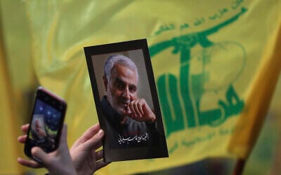Illustrative: A supporter of the Hezbollah terror group uses her mobile phone to takes a picture of photo of slain Iranian Revolutionary Guard Gen. Qassem Soleimani during a ceremony marking the anniversary of the assassination of Hezbollah leaders, Abbas al-Moussawi, Ragheb Harb and Imad Mughniyeh and the end of a 40-day Muslim mourning period for Soleimani, in the southern suburb of Beirut, Lebanon, February 16, 2020. (AP Photo/Hassan Ammar)